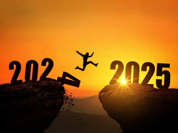 Silhouette eines springenden Menschen, der von 2024 zu 2025 springt, im Hintergrund die aufgehende Sonne